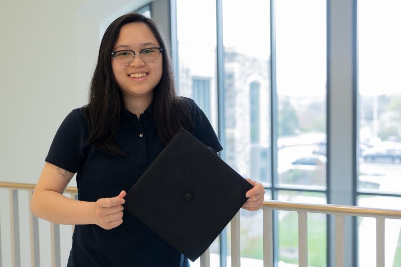 Computer engineering student Jenny Li holds a graduation cap.